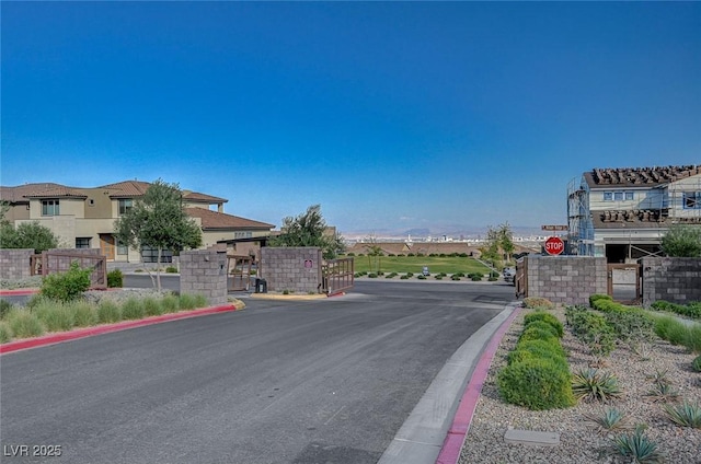 view of road with a gate, curbs, and a gated entry