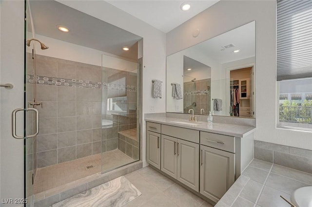 full bathroom with visible vents, vanity, a shower stall, tile patterned floors, and a walk in closet