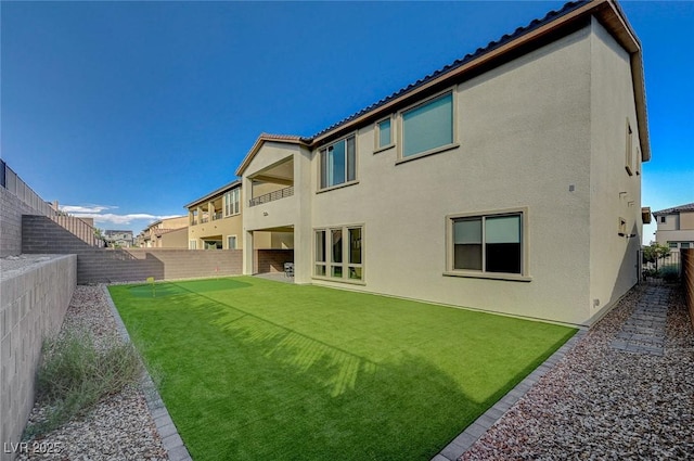 back of property featuring a tile roof, a fenced backyard, a lawn, and stucco siding