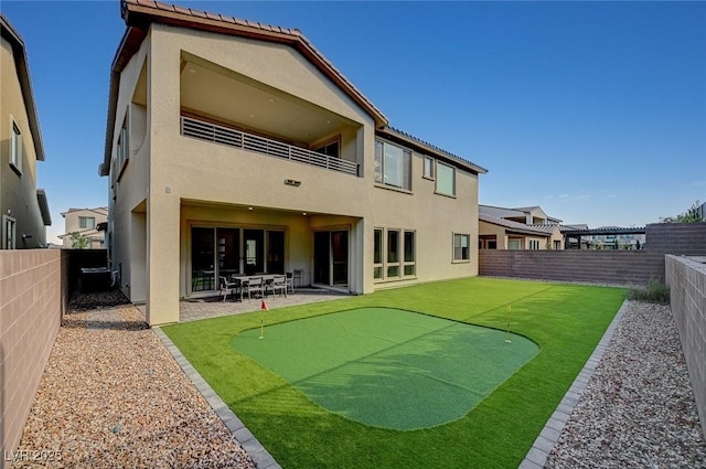 rear view of house featuring a fenced backyard, a balcony, and stucco siding