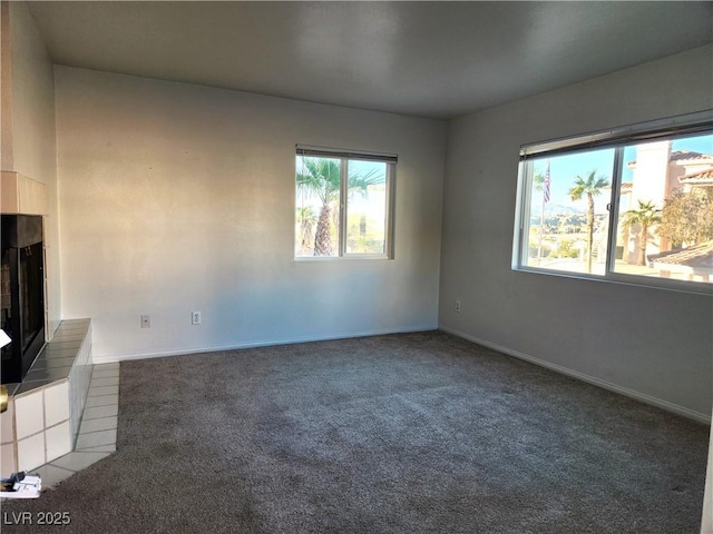 unfurnished living room featuring carpet floors, a fireplace, and baseboards