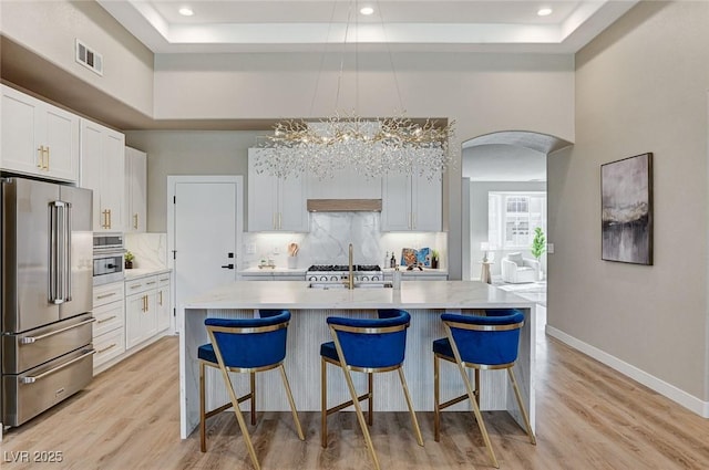 kitchen featuring arched walkways, a tray ceiling, high end refrigerator, and visible vents