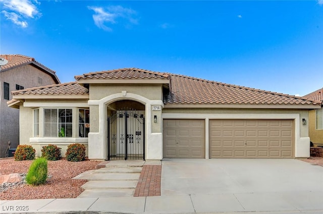 mediterranean / spanish-style house with a garage, concrete driveway, and stucco siding