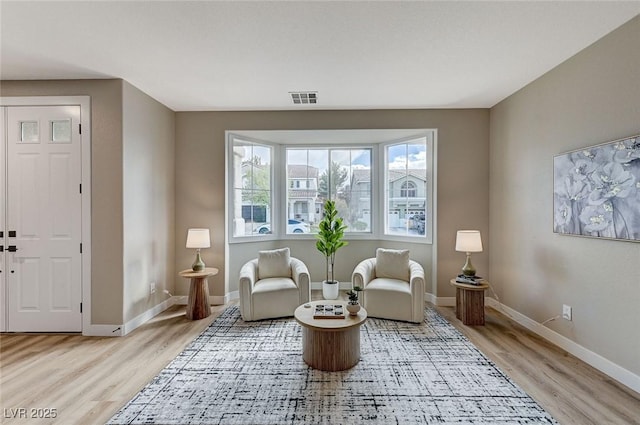 sitting room featuring light wood finished floors, visible vents, and baseboards