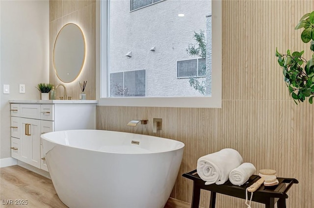 full bathroom featuring wood finished floors, a freestanding tub, and vanity