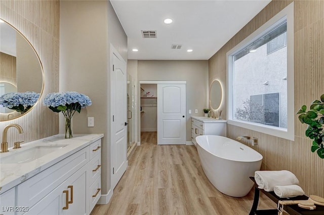 bathroom with two vanities, visible vents, a sink, and wood finished floors