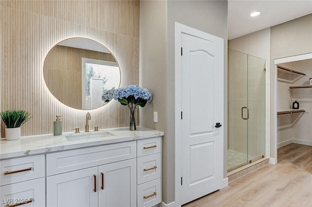 bathroom featuring recessed lighting, wood finished floors, vanity, a spacious closet, and a shower stall