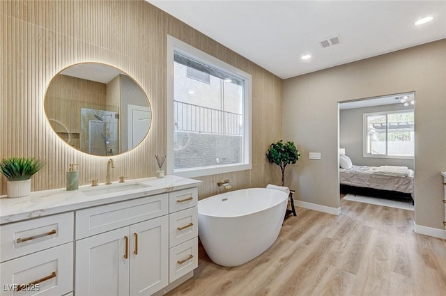 ensuite bathroom with a walk in shower, visible vents, vanity, and wood finished floors