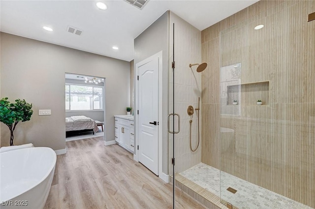 bathroom featuring visible vents, ensuite bathroom, wood finished floors, tiled shower, and baseboards