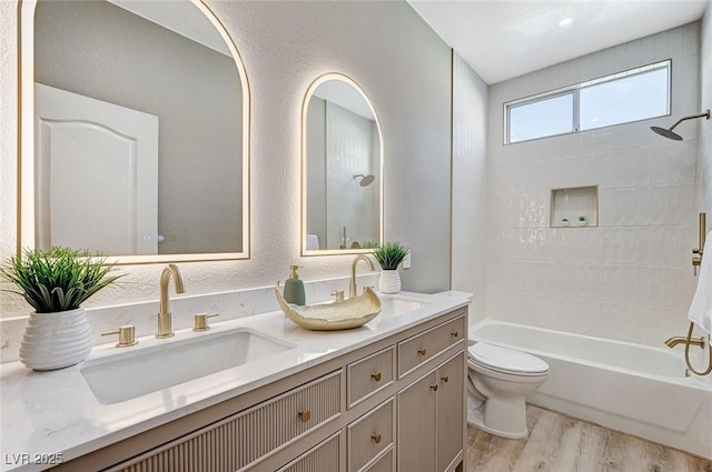 full bathroom featuring double vanity, a sink, toilet, and wood finished floors