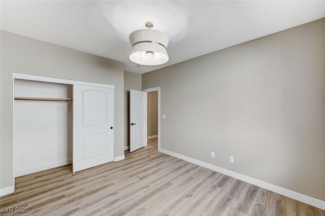 unfurnished bedroom featuring baseboards, a closet, and wood finished floors