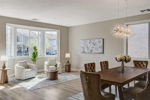 dining space with baseboards, visible vents, an inviting chandelier, and wood finished floors