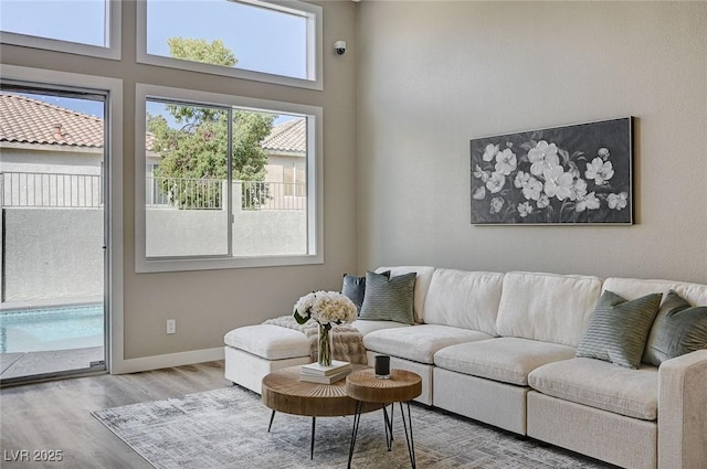 living room with a high ceiling, wood finished floors, and baseboards