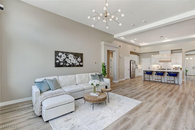 living area featuring light wood-type flooring, baseboards, a chandelier, and recessed lighting