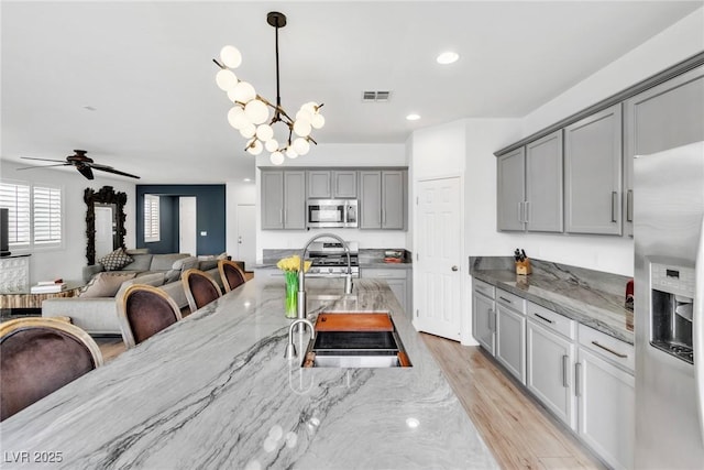 dining space with recessed lighting, visible vents, light wood-style flooring, and ceiling fan with notable chandelier