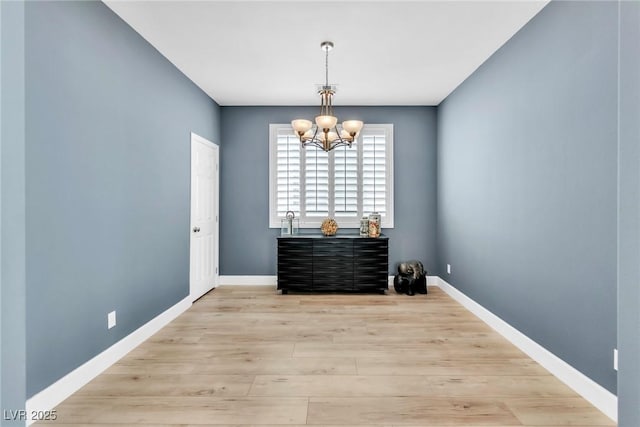 unfurnished dining area featuring a chandelier, baseboards, and light wood-style flooring