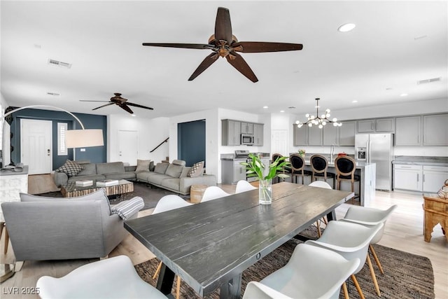 dining room with light wood finished floors, visible vents, recessed lighting, and ceiling fan with notable chandelier