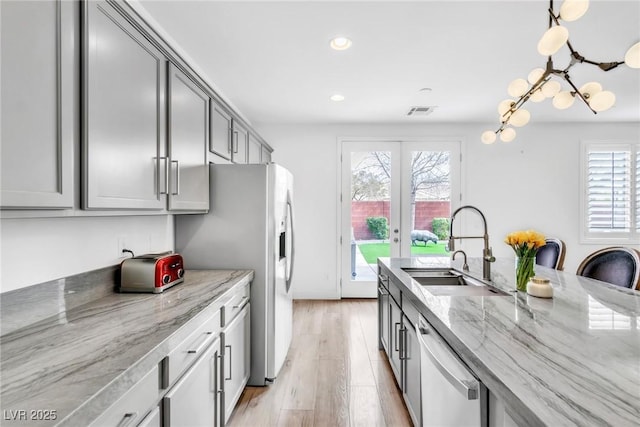 kitchen with dishwashing machine, light stone counters, gray cabinetry, a sink, and french doors