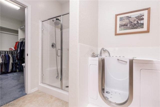 full bath with a bathing tub, a shower stall, a walk in closet, and tile patterned floors