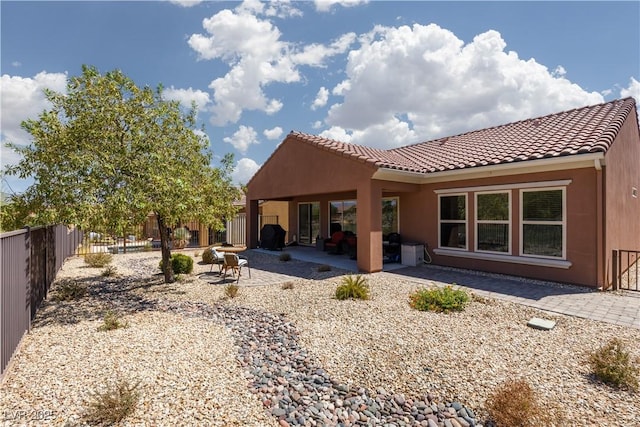 back of house featuring a patio area, a fenced backyard, a tile roof, and stucco siding