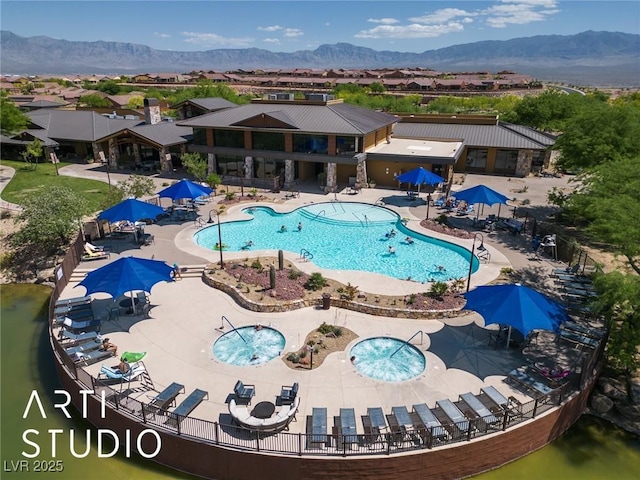 pool with a patio area, a mountain view, and fence