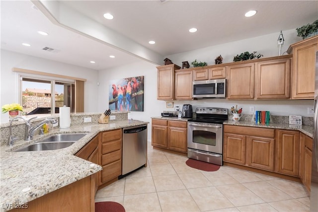 kitchen featuring light stone counters, light tile patterned flooring, recessed lighting, a sink, and appliances with stainless steel finishes