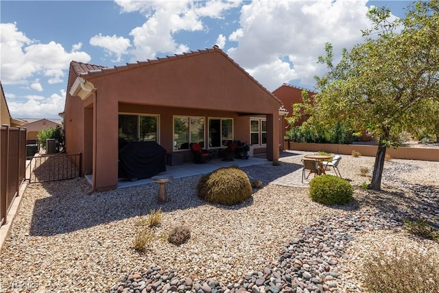 rear view of house with a patio area, fence, a tile roof, and stucco siding