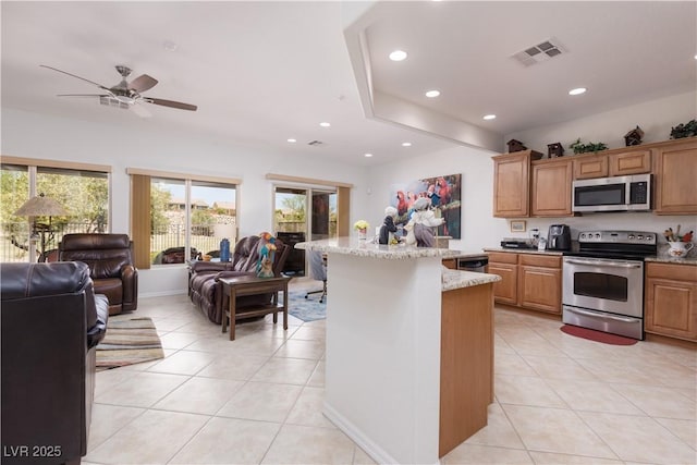 kitchen featuring light tile patterned floors, visible vents, open floor plan, light stone countertops, and stainless steel appliances