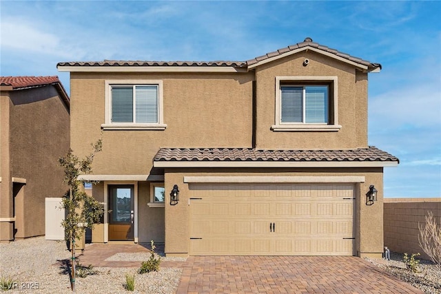 view of front of home with decorative driveway, a tiled roof, an attached garage, and stucco siding