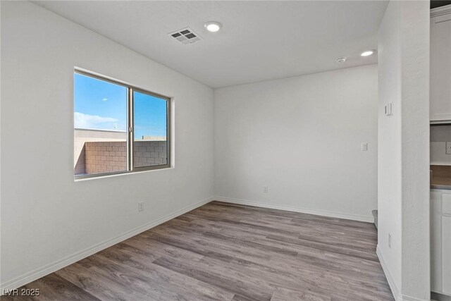 unfurnished room featuring recessed lighting, wood finished floors, visible vents, and baseboards