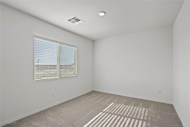 carpeted spare room with visible vents and baseboards