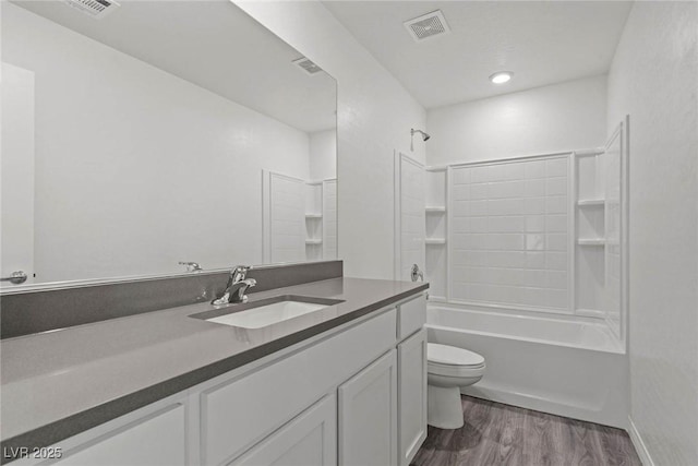 bathroom with visible vents, toilet, wood finished floors, vanity, and shower / washtub combination