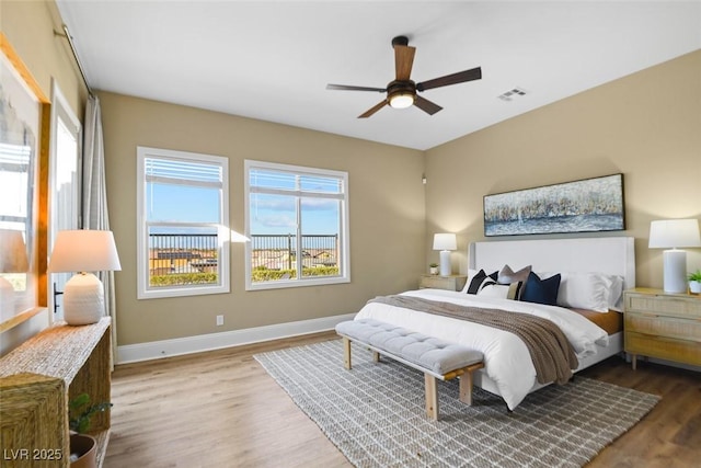 bedroom with a ceiling fan, wood finished floors, visible vents, and baseboards