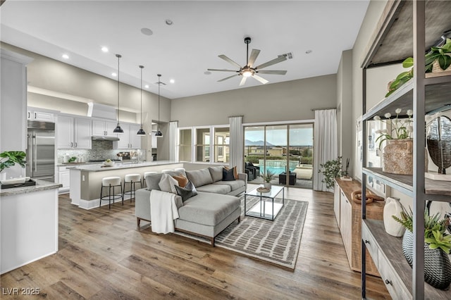 living room featuring recessed lighting, a ceiling fan, wood finished floors, and a towering ceiling