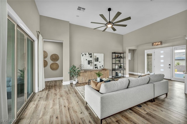 living room with ceiling fan, wood finished floors, visible vents, and baseboards