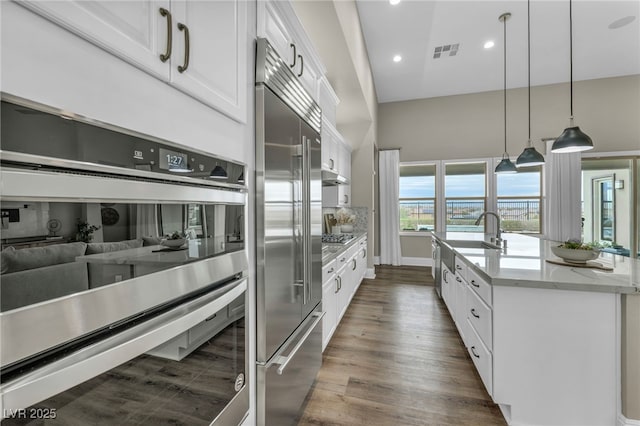 kitchen featuring visible vents, dark wood-style flooring, stainless steel appliances, and white cabinetry