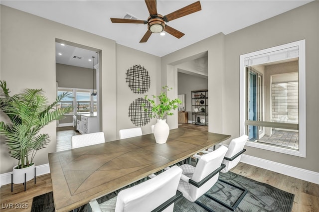 dining room with visible vents, baseboards, wood finished floors, and a ceiling fan