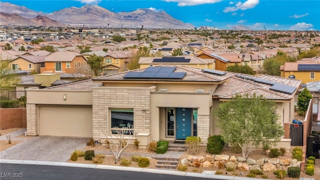 view of front of house with a mountain view, a residential view, roof mounted solar panels, and a garage