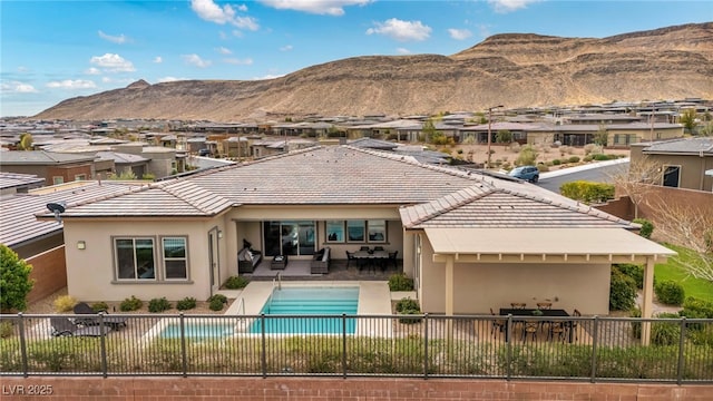 rear view of house featuring a fenced in pool, stucco siding, a fenced backyard, a mountain view, and a patio