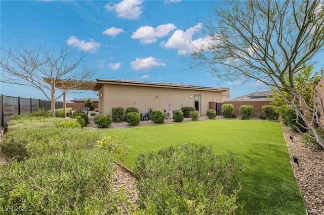 back of house featuring stucco siding, a yard, and a fenced backyard