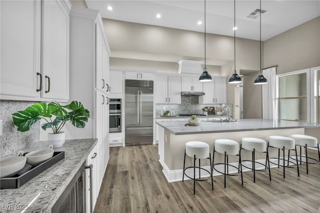 kitchen with visible vents, a sink, stainless steel appliances, white cabinets, and light wood-type flooring