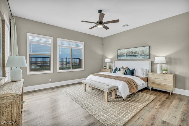 bedroom with ceiling fan, wood finished floors, visible vents, and baseboards