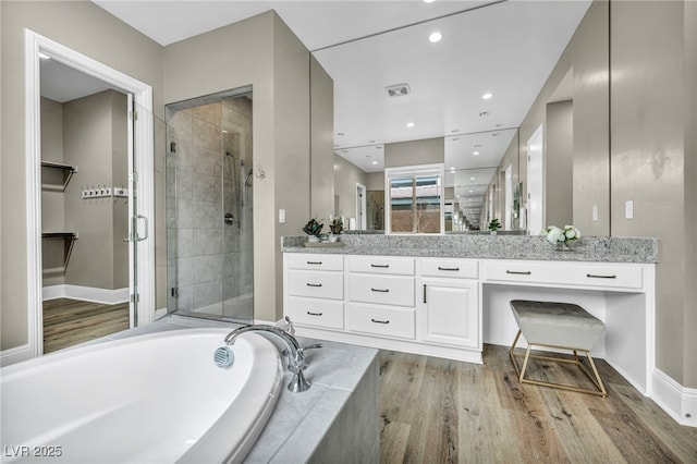 bathroom featuring visible vents, a garden tub, a stall shower, wood finished floors, and vanity