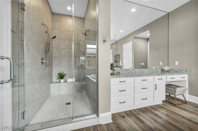 bathroom featuring vanity, wood finished floors, baseboards, recessed lighting, and a stall shower