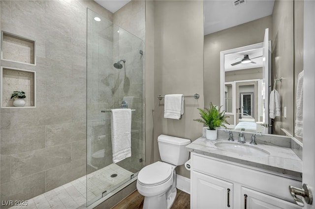 bathroom with a stall shower, toilet, vanity, and wood finished floors