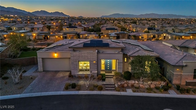 view of front of property with decorative driveway, a mountain view, a residential view, a garage, and solar panels