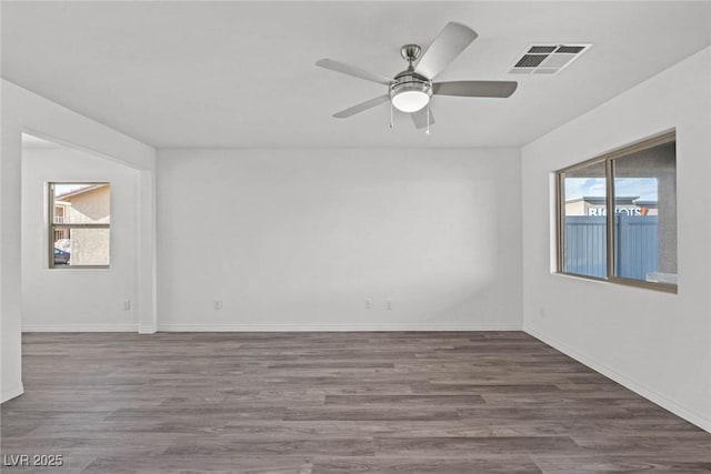 empty room with a ceiling fan, baseboards, visible vents, and wood finished floors