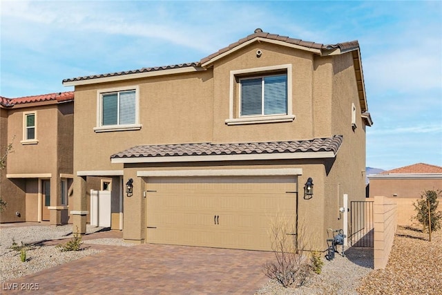 view of front of home with a garage, decorative driveway, a tiled roof, and stucco siding