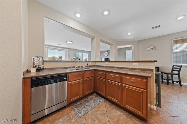 kitchen featuring visible vents, dishwasher, brown cabinets, a healthy amount of sunlight, and a sink