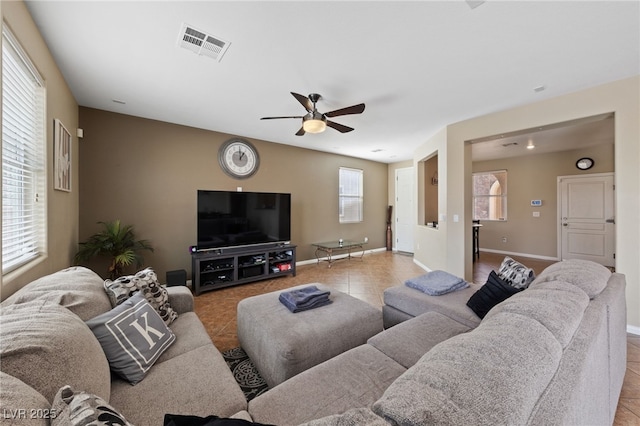 living area with a wealth of natural light, visible vents, baseboards, and light tile patterned floors